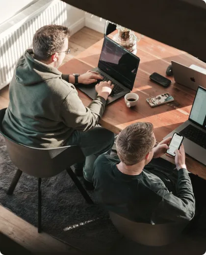 Blick von oben auf zwei Arbeitsplätze mit Laptops an einem runden Tisch.